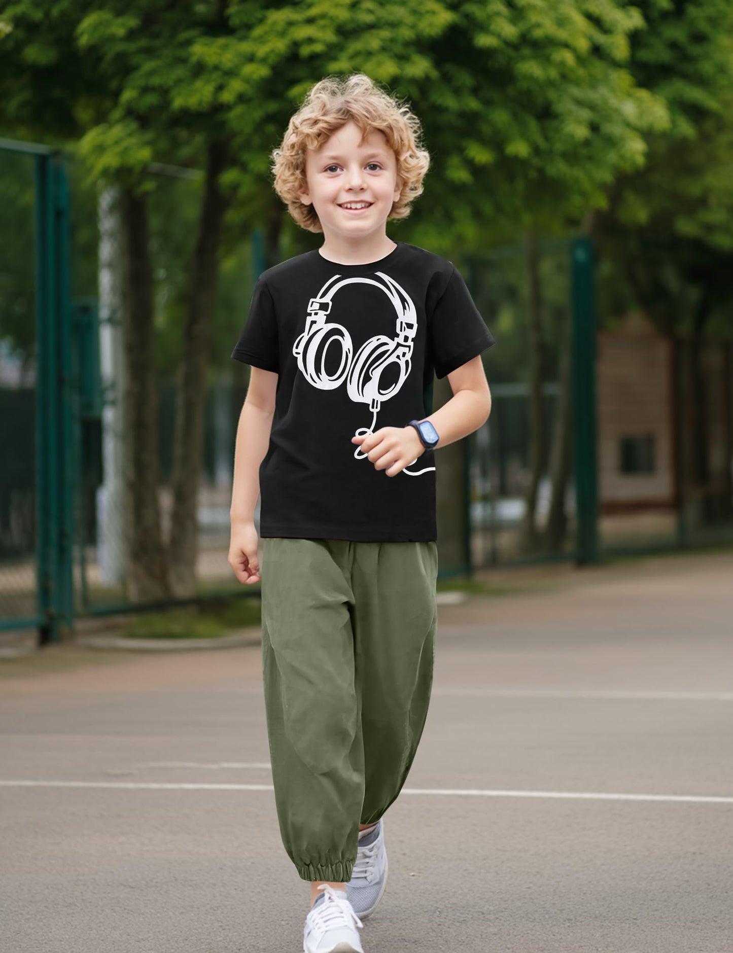 Child wearing a black t-shirt with a white graphic design outdoors on a playground.