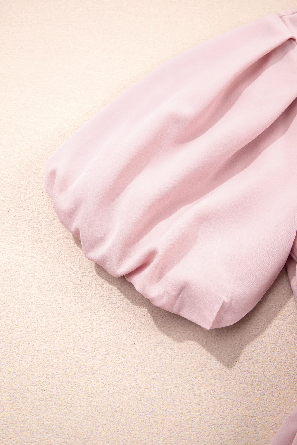Pink satin pillow on a beige background