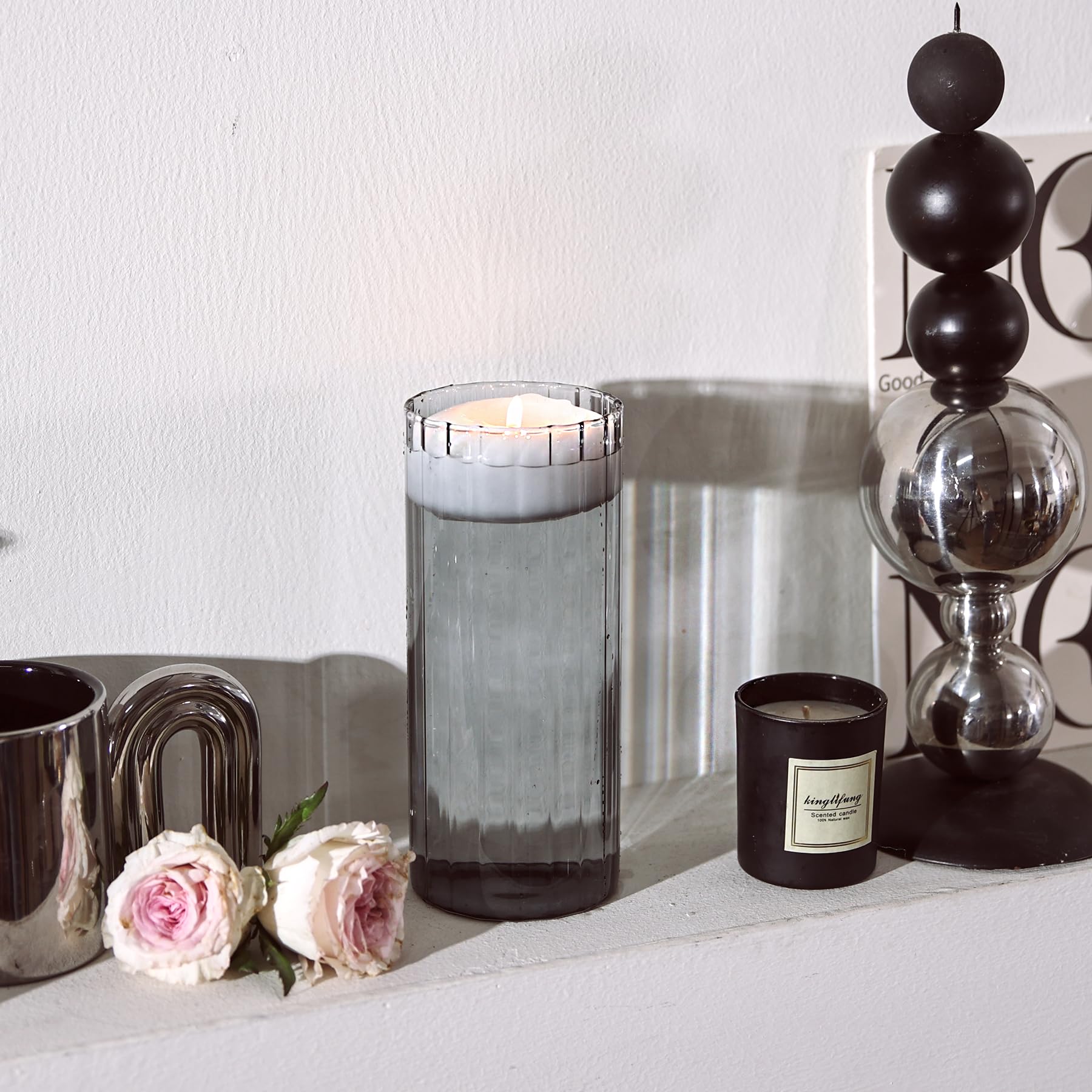 Decorative items including a candle, flowers, and a vase on a surface with a neutral background.