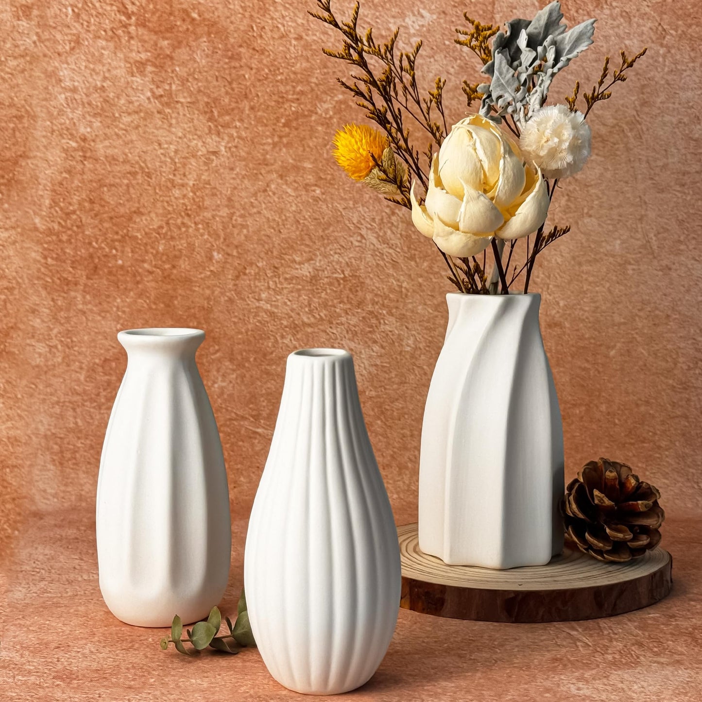 Three white vases on a wooden surface with a brown background
