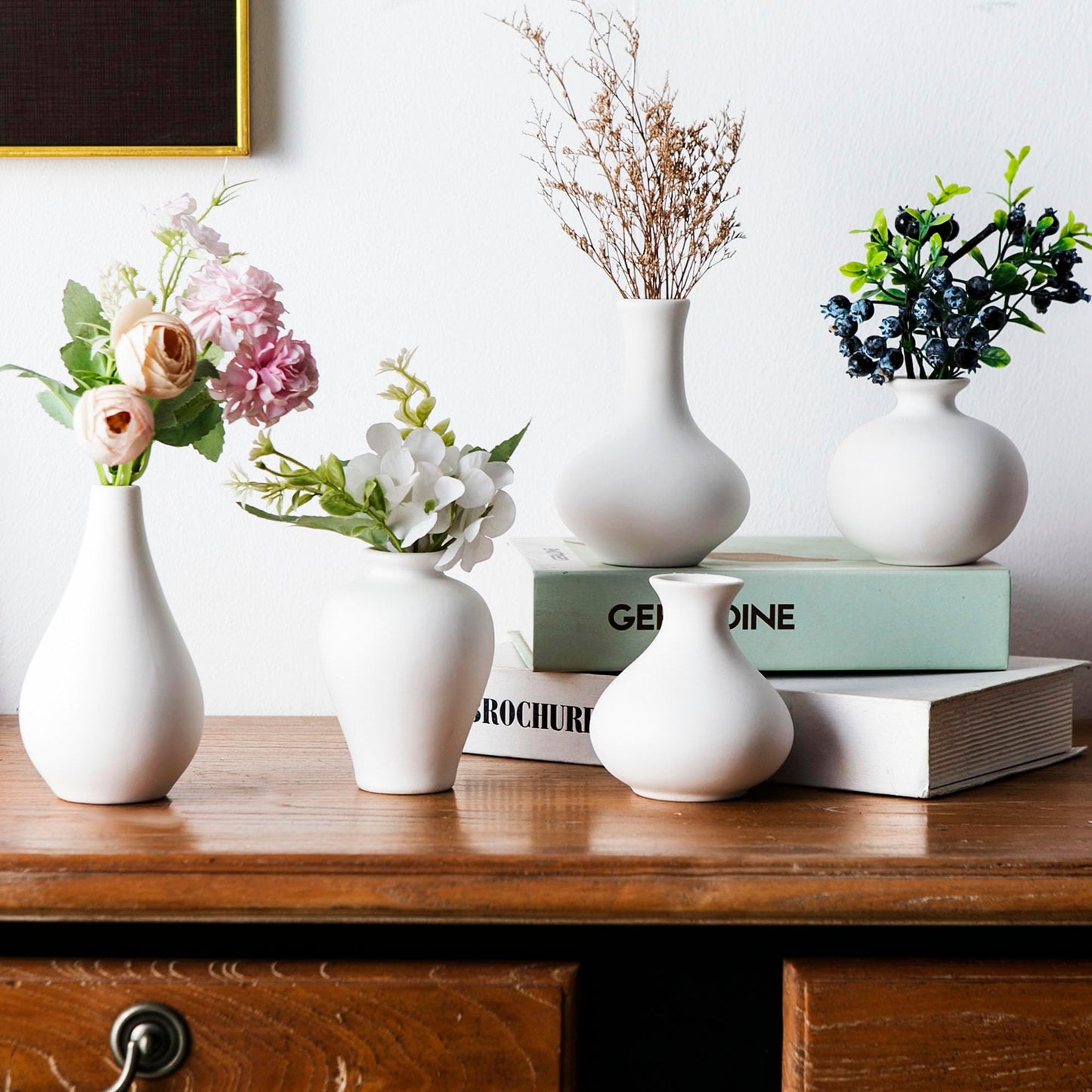 Set of white vases with floral arrangements on a wooden surface