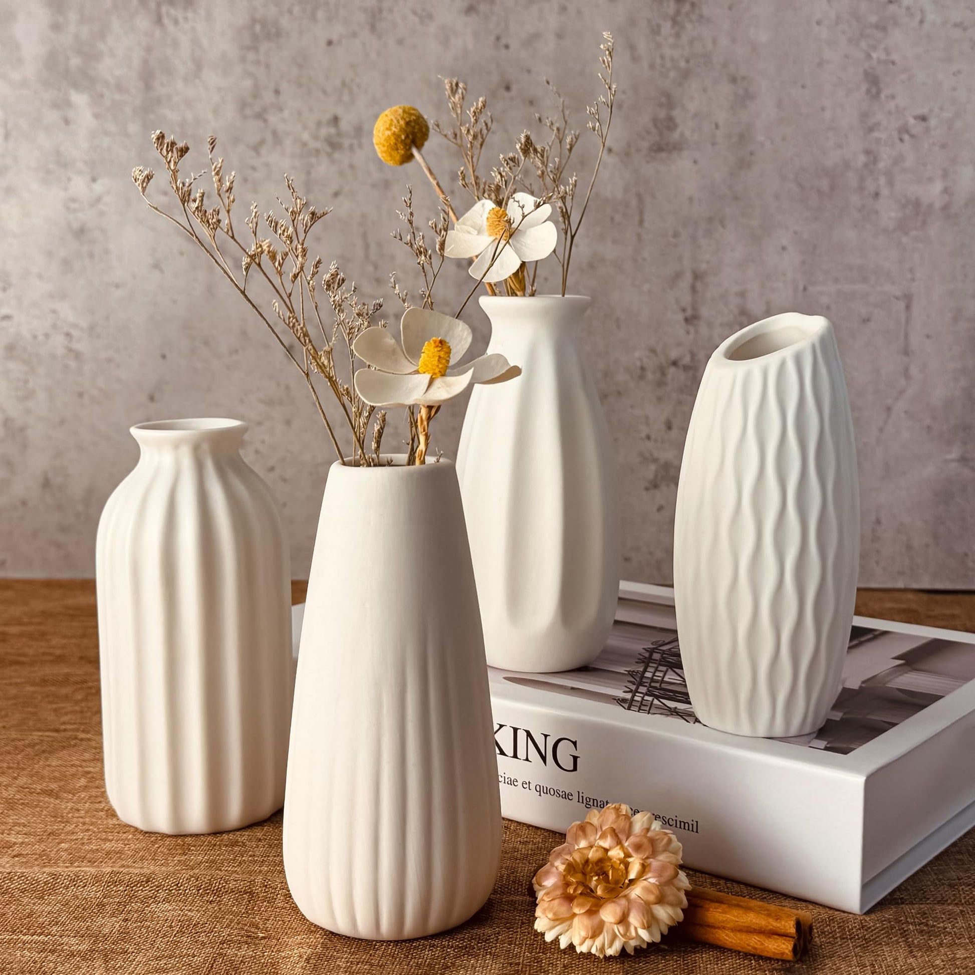 Set of white ceramic vases with textured designs on a wooden surface.