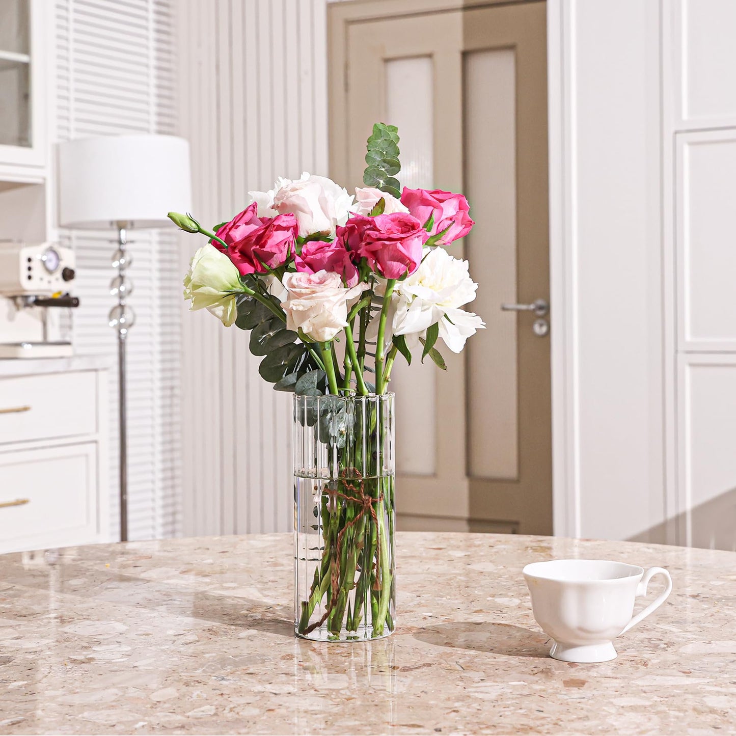 Clear vase with pink, white, and green flowers on a marble countertop in a kitchen.
