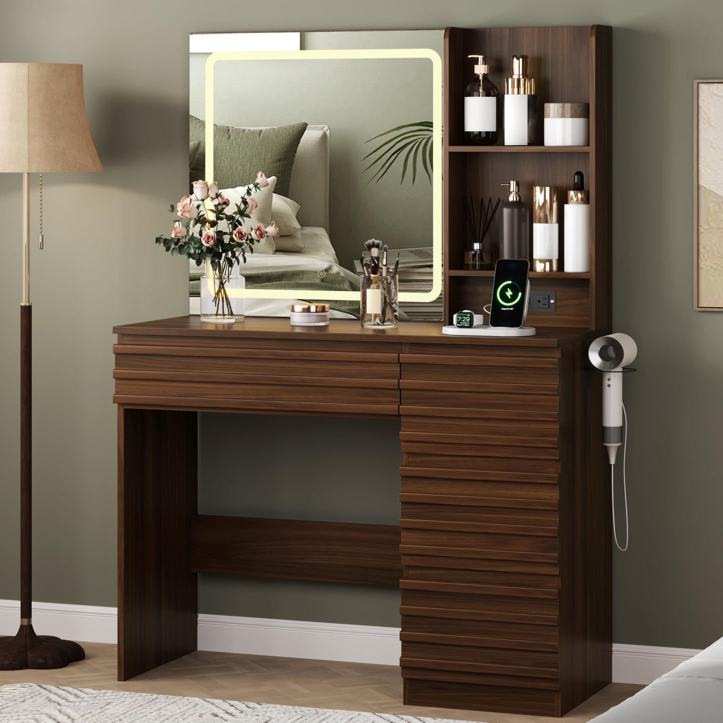 Wooden vanity with mirror, lights, and various items on a neutral-colored wall.
