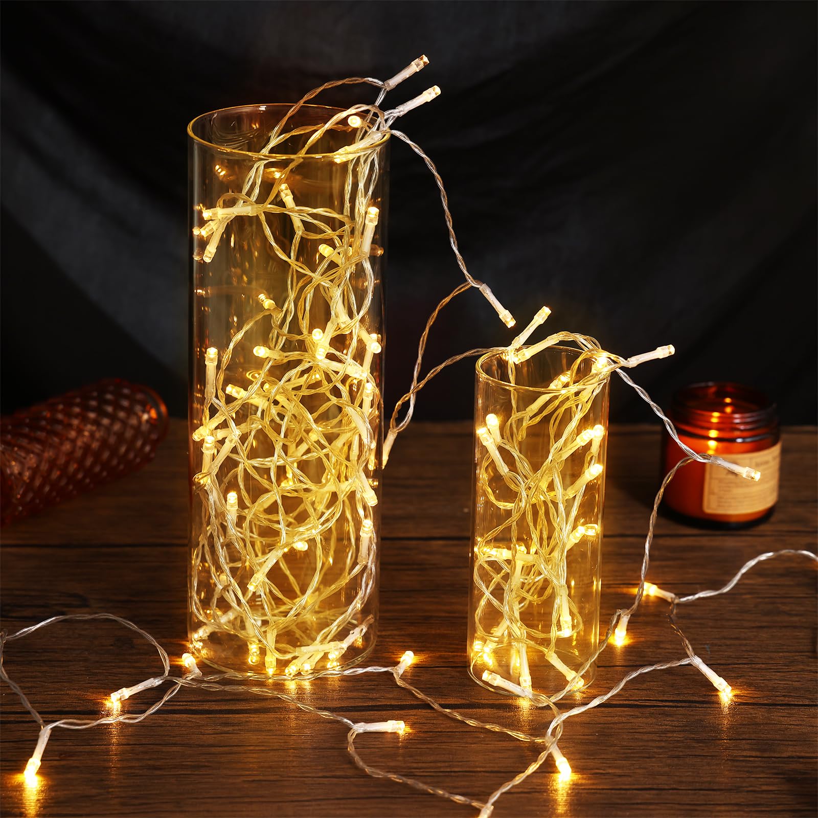 String lights in glass containers on a wooden surface with a dark background