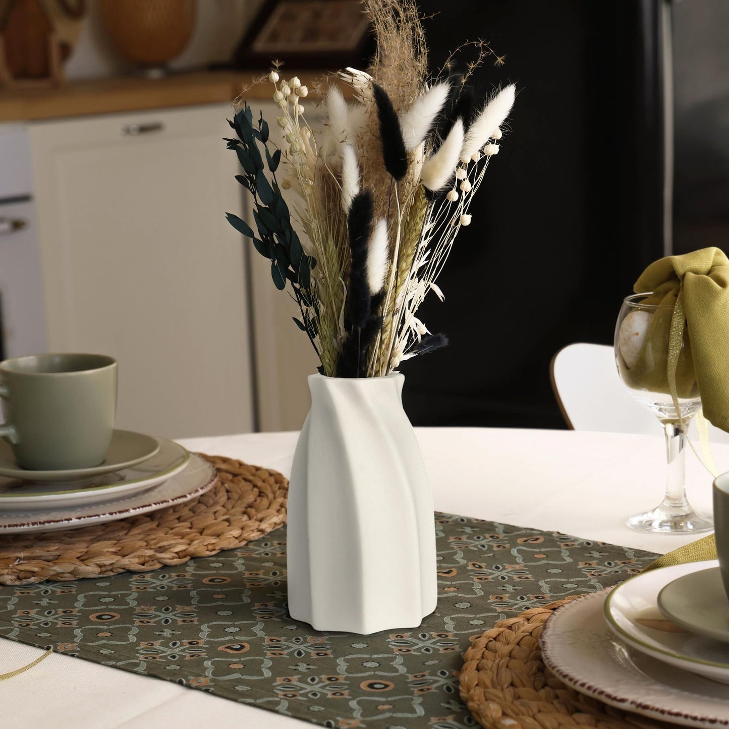 White vase with dried plants on a decorated table