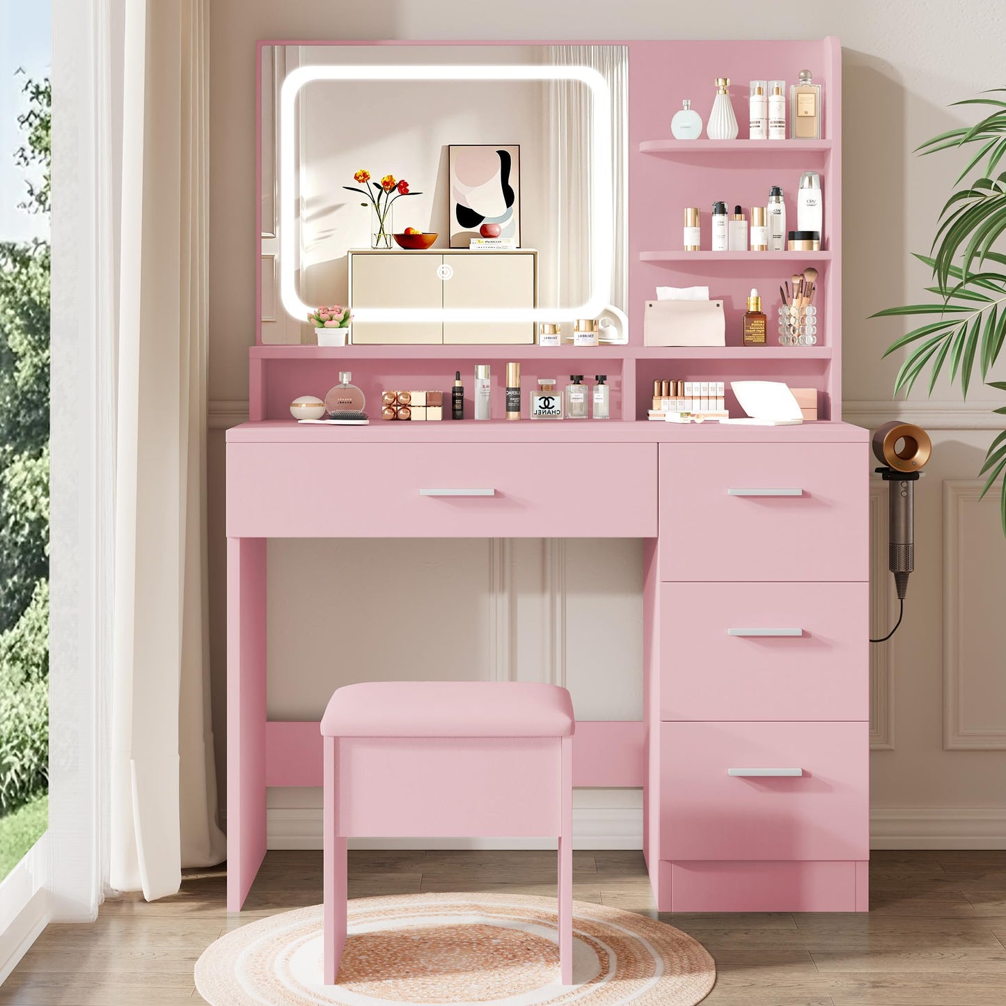 Pink vanity table with mirror and stool in a room with plants and window.