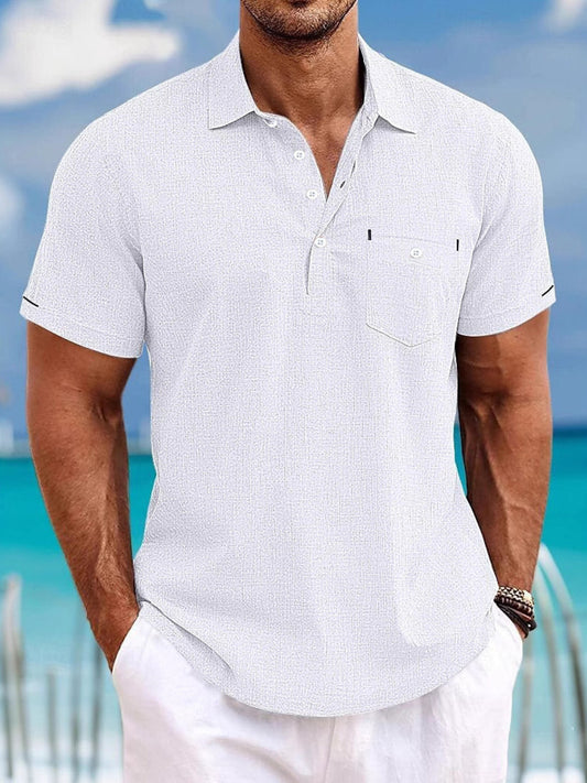 Man wearing a light gray short-sleeve shirt with a blurred beach background