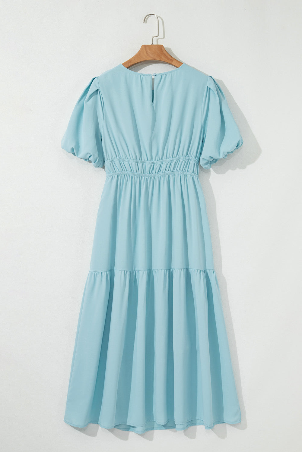 Light blue dress on a wooden hanger against a white background
