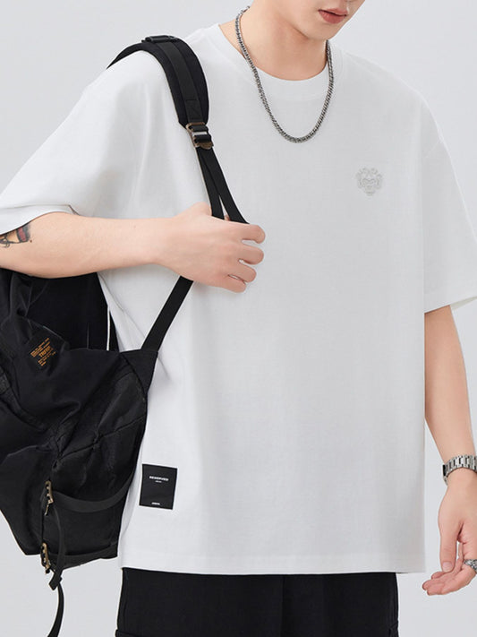 Person wearing a white oversized shirt with a black backpack on a light gray background